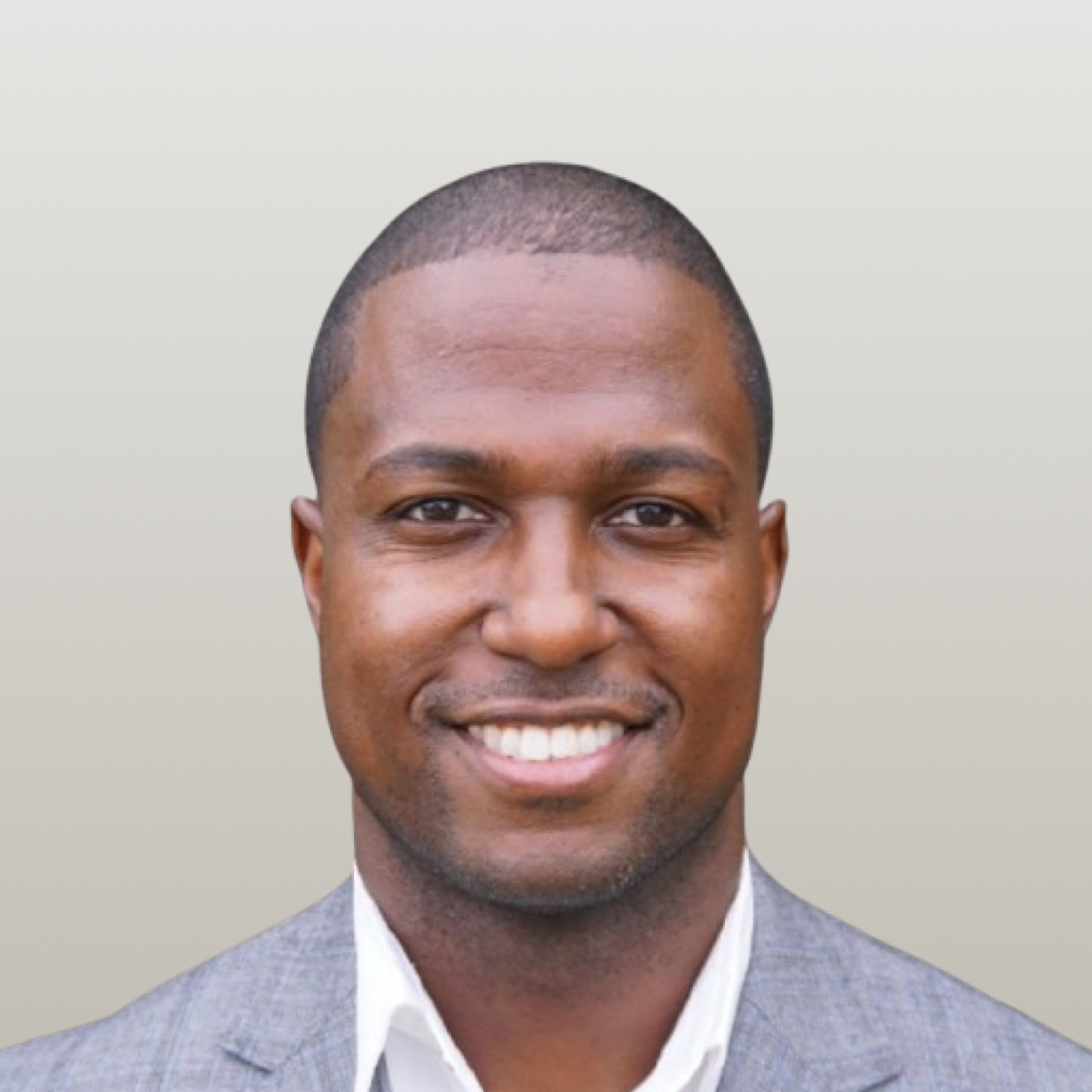 Headshot of a smiling man in a gray suit jacket over a white shirt.