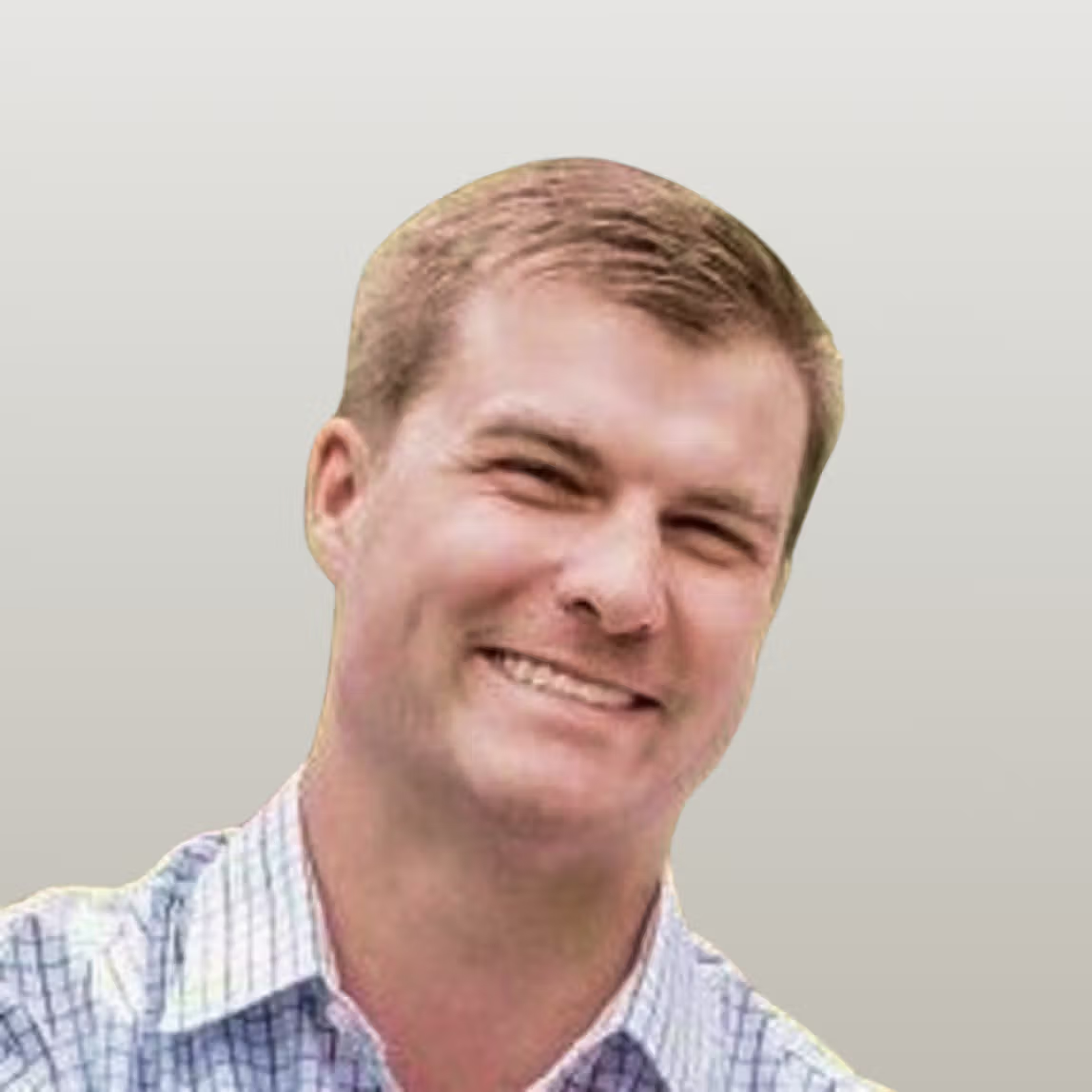 Smiling man with short light brown hair wearing a plaid shirt.