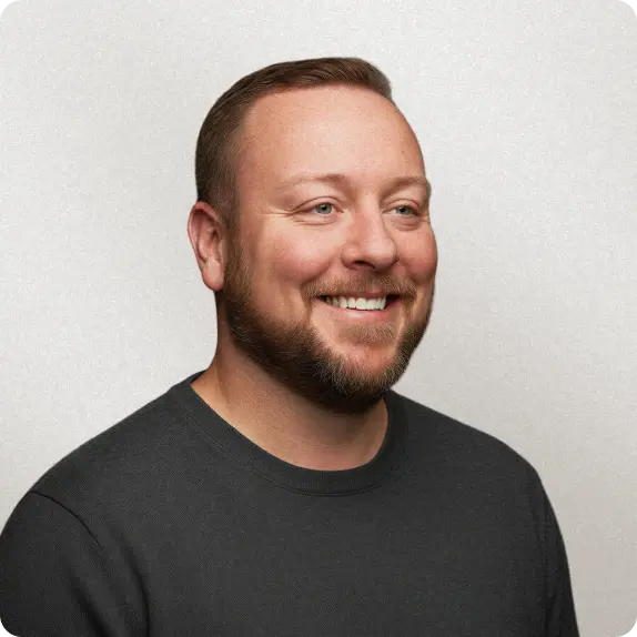 A smiling man with a beard in a blue shirt against a blue background.