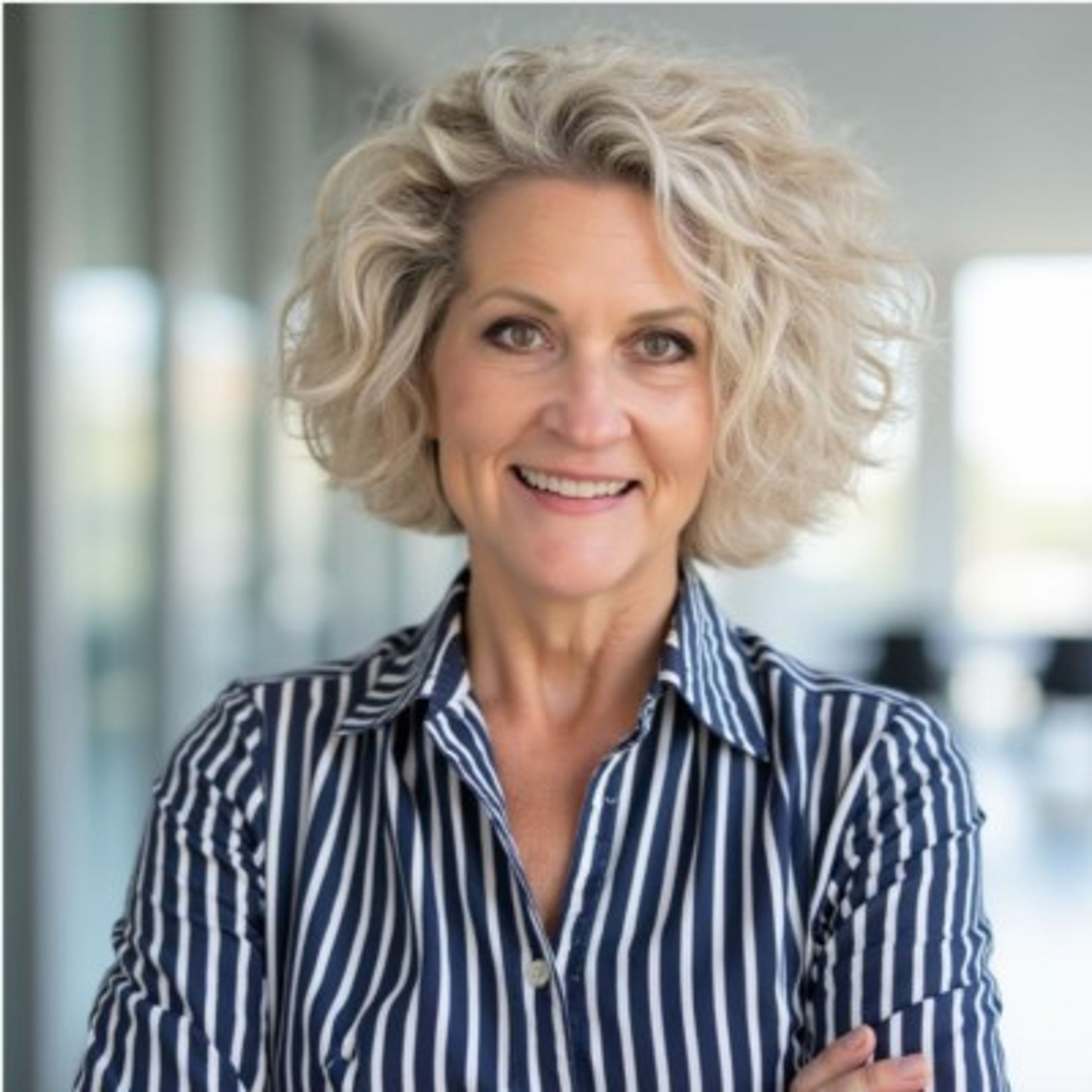 Smiling woman with short, curly blonde hair wearing a striped shirt.