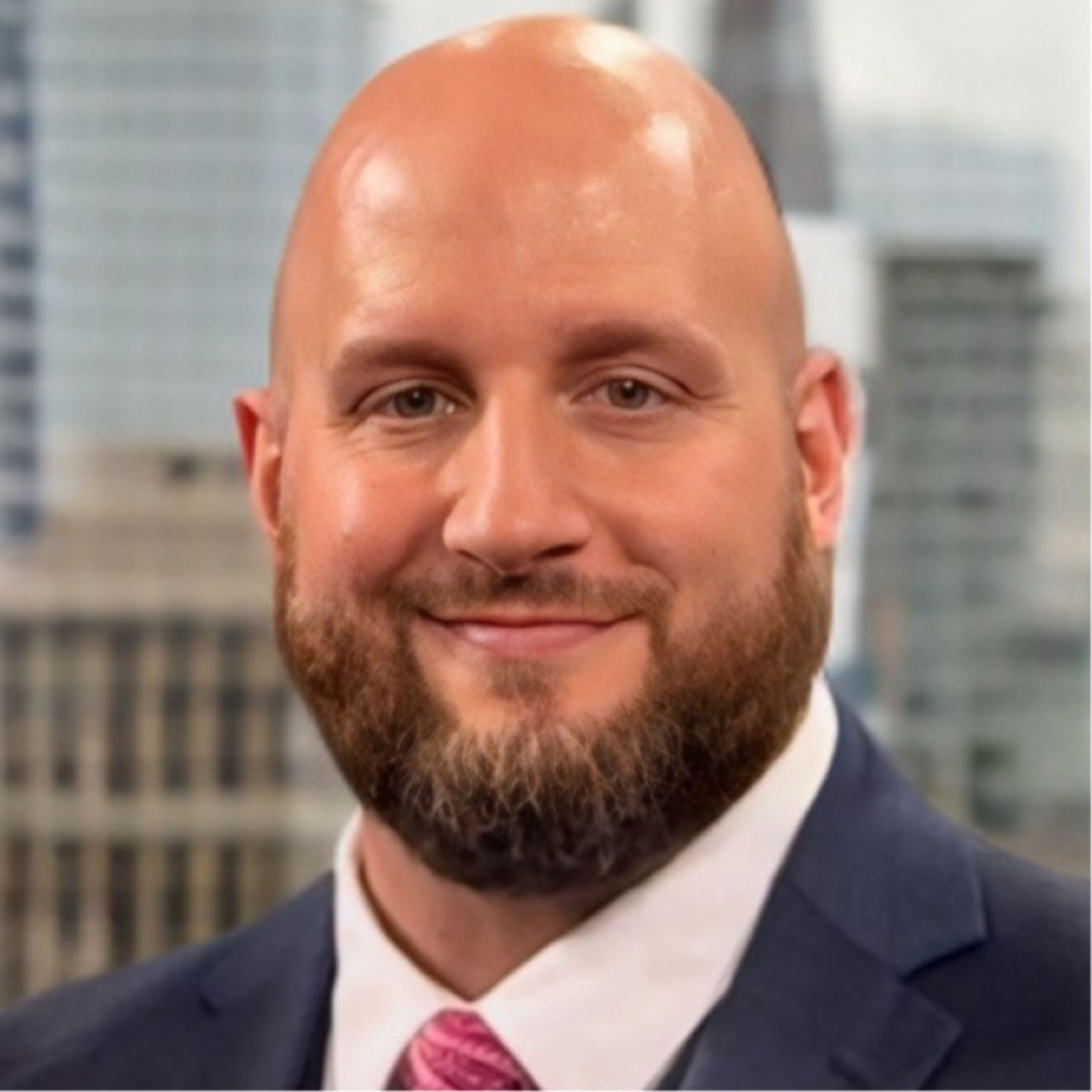 Smiling bald man with a beard wearing a suit.