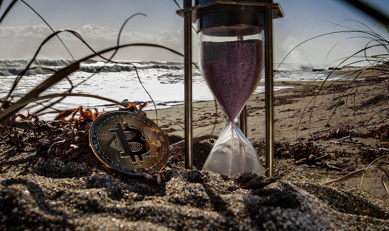 timeglass og bitcoin på en strand