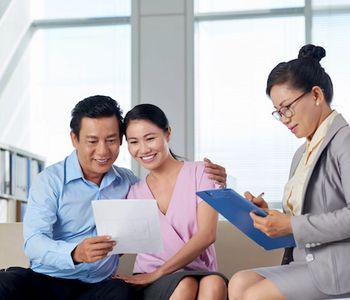 Asian couple going over MRP certification with VA Loan specialist.