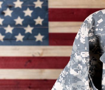 Military standing in front of American flag.