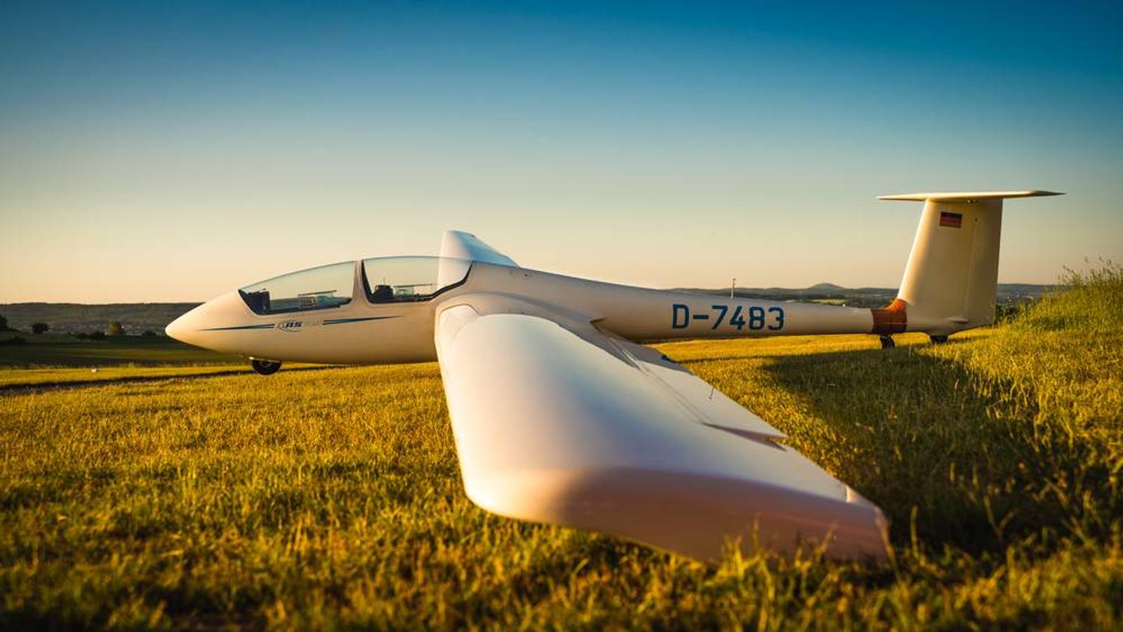 Segelflugzeug am Boden neben einem abgeernteten Feld