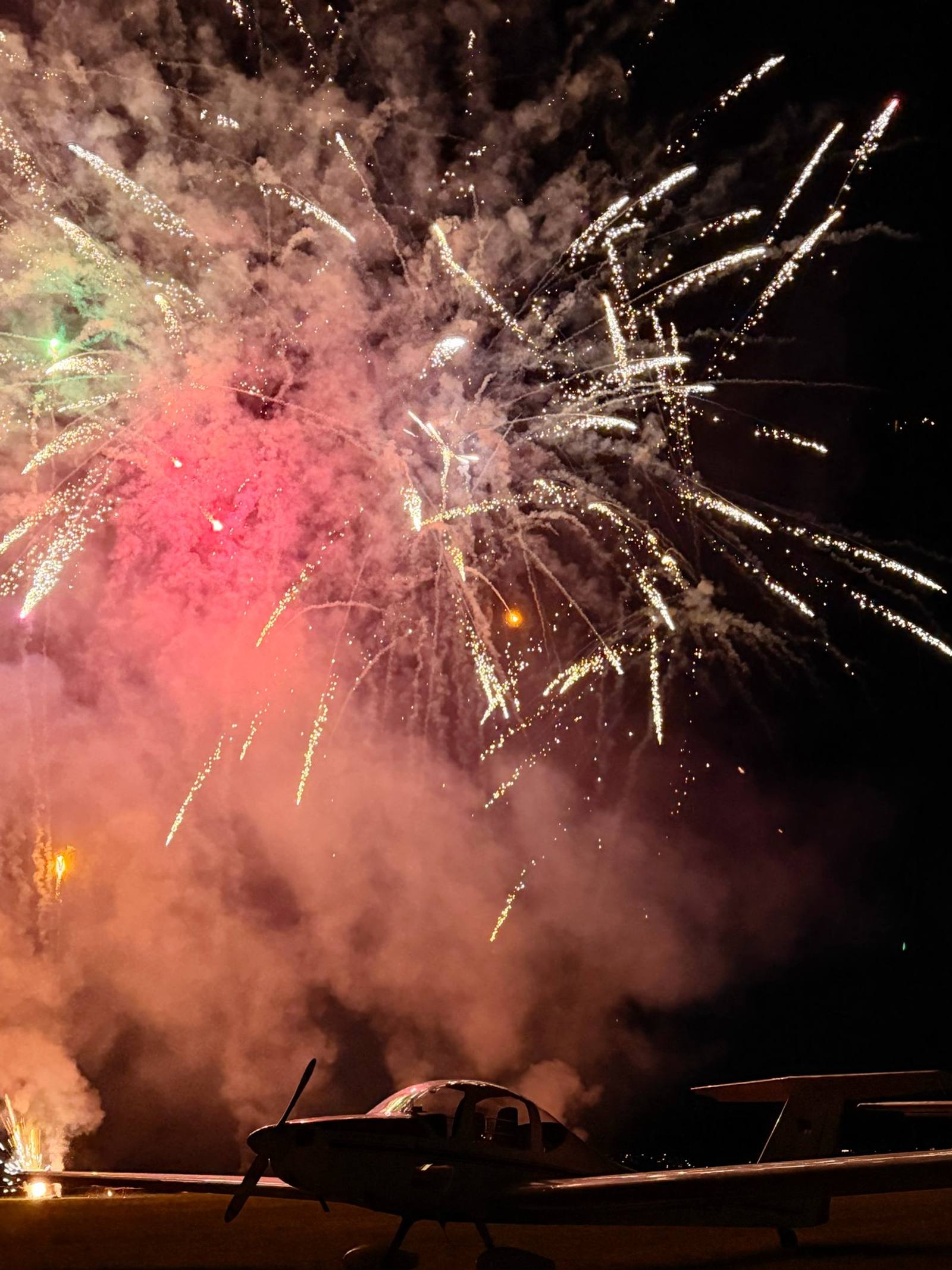 Feuerwerk über dem Flugplatz, davor ein Flugzeug