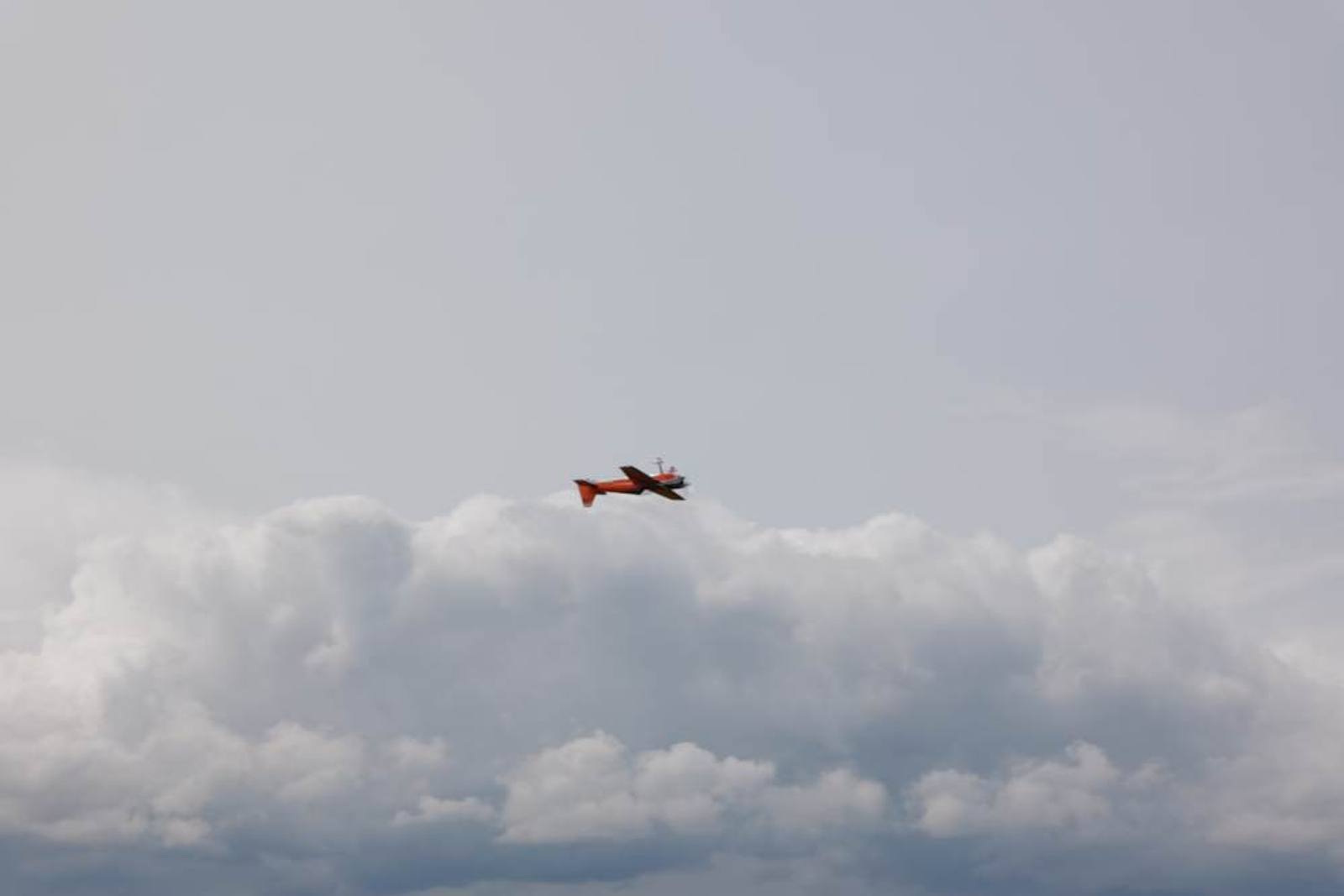 Flugzeug klein vor einer Wolkenwand