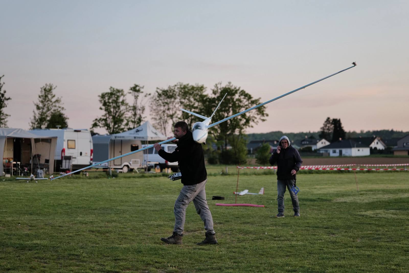 Ein Pilot trägt sein Modellflugzeug auf der Schulter