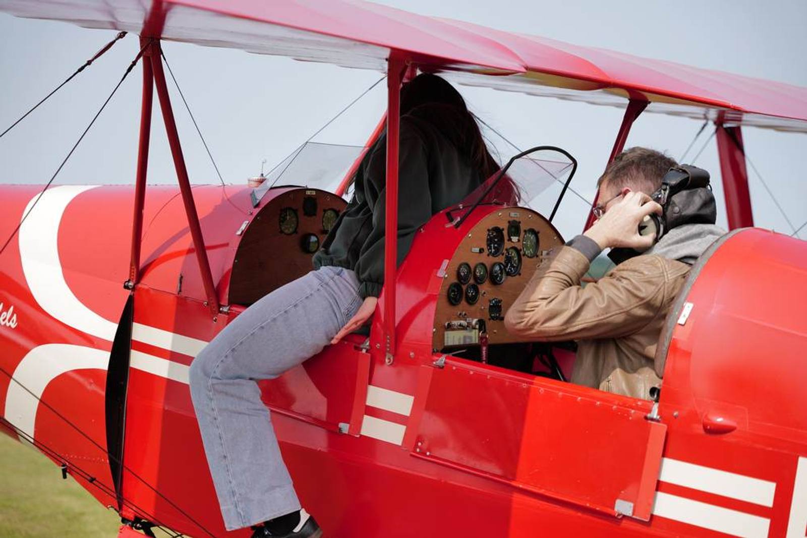 Zwei Personen im offenen Cockpit eines Doppeldeckers