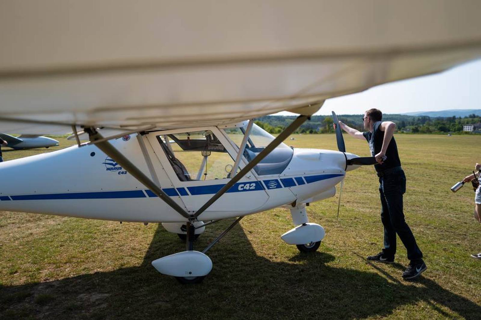 Person am Propeller eines Ultraleichtflugzeugs