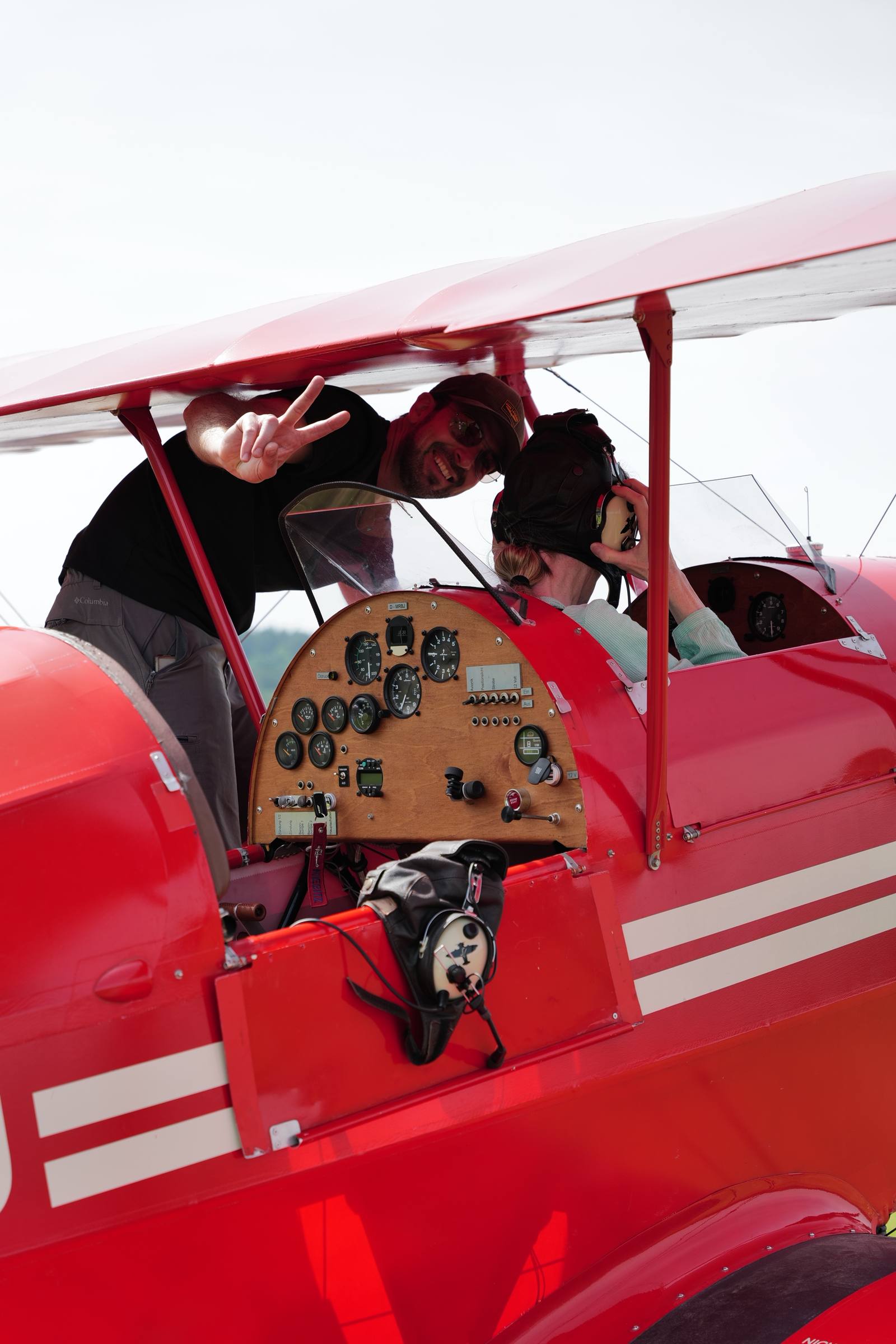 Ein Pilot steht auf der Fläche des Doppeldeckers und grinst in die Kamera