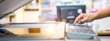  A hand operates a photocopier with its lid open, suggesting a print environment symbolising print advertising