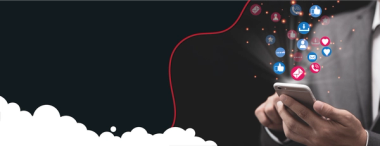  A person in a suit holds a smartphone, from which various social media icons (likes, hearts, messages, followers, etc., in red, blue, and white) are digitally emanating and floating upwards. The background is dark, with a red wavy line and white cloud shapes at the bottom.