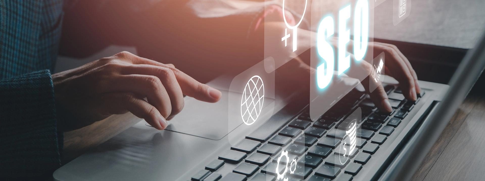 A person's hands are typing on a laptop keyboard, with a prominent glowing "SEO" text and various digital icons, including a location pin and a gear, floating above the screen, representing local SEO strategies and optimisation.