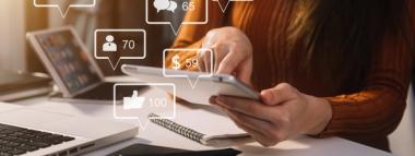 colleagues talking about social media  A person is simultaneously interacting with a laptop and a tablet, surrounded by floating white social media engagement icons displaying numbers (e.g., likes, followers, comments, revenue), symbolizing social media strategy and consultancy.
