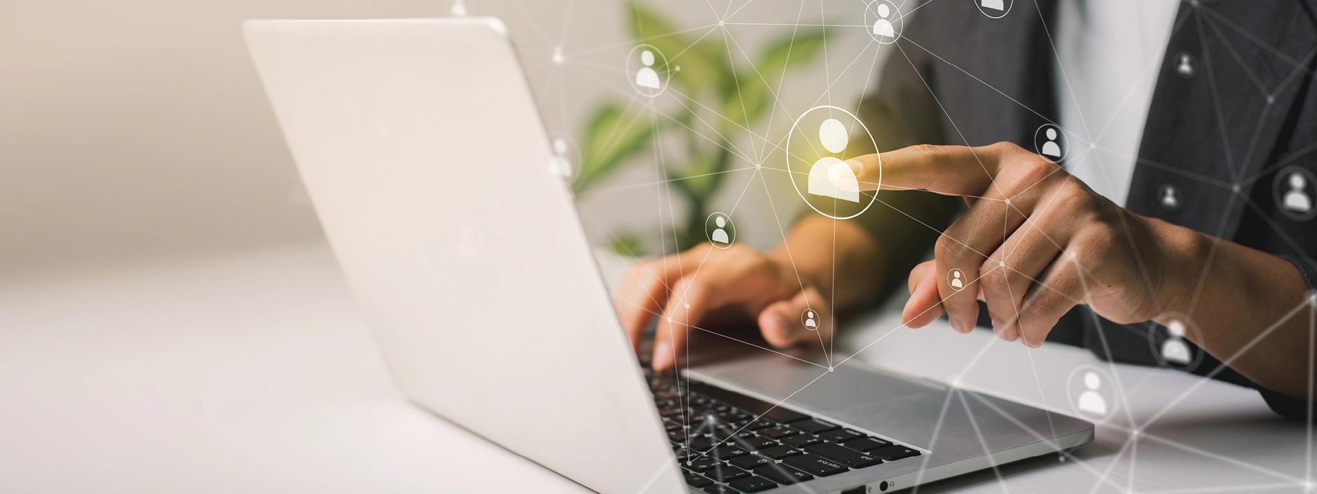 Hands on a laptop with a digital network of people, implying outsourcing or remote collaboration.