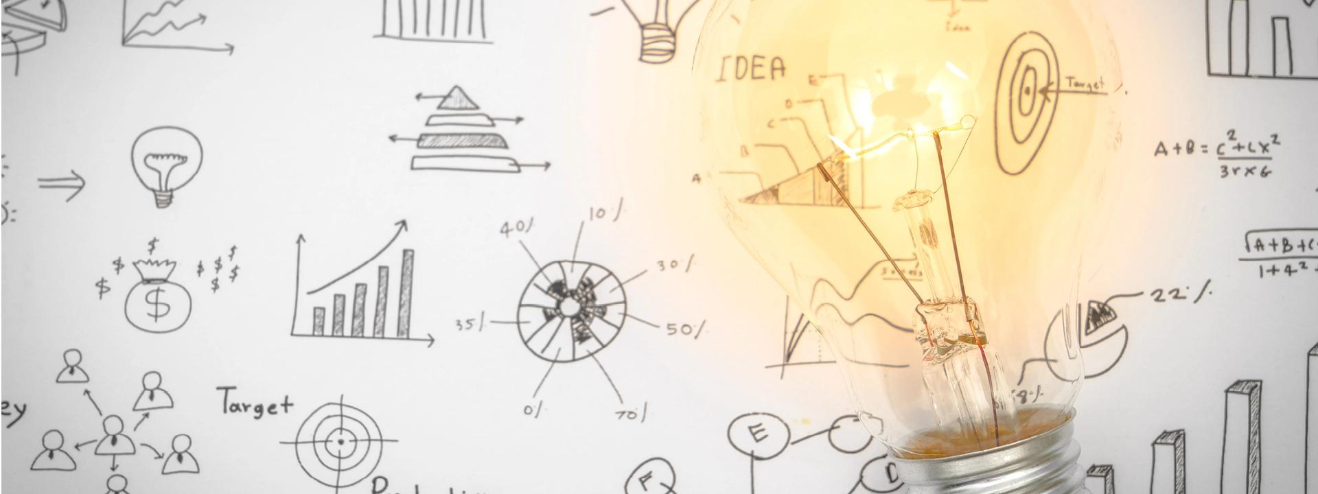 A bright lightbulb illuminating a white surface covered with various hand-drawn business and project sketches, including charts, graphs, a target, and the word 'IDEA'