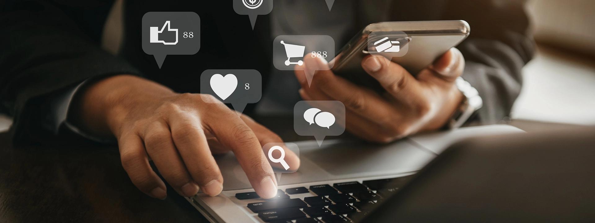 A person is simultaneously using a laptop and a smartphone, with social media icons like likes, hearts, comments, and shopping carts floating around them, symbolising social media management and interaction.