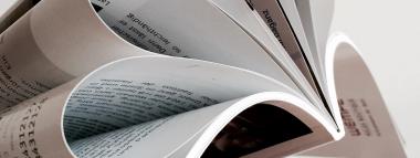  A close-up shot shows the fanned- A close-up shot shows the fanned-out pages of a printed publication, revealing text and images, suggesting editorial or publishing content.pages of a printed publication, revealing text and images, suggesting editorial or publishing content.