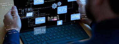 A person is holding a laptop displaying lines of code, with several glowing blue overlay icons related to web development, including HTML tags, gears, angle brackets, and a padlock, symbolising website creation, coding, and security.