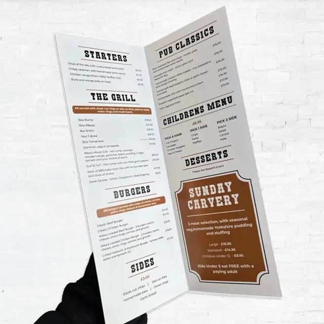 A person's hand holding open a pub menu
