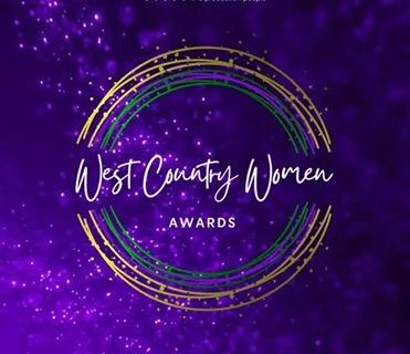 The image displays the logo for the "West Country Women Awards" on a sparkling purple background. The text "West Country Women" is in a white script font, with "AWARDS" in a smaller, white sans-serif font below it. These words are encircled by three abstract, textured rings in gold, green, and purple.