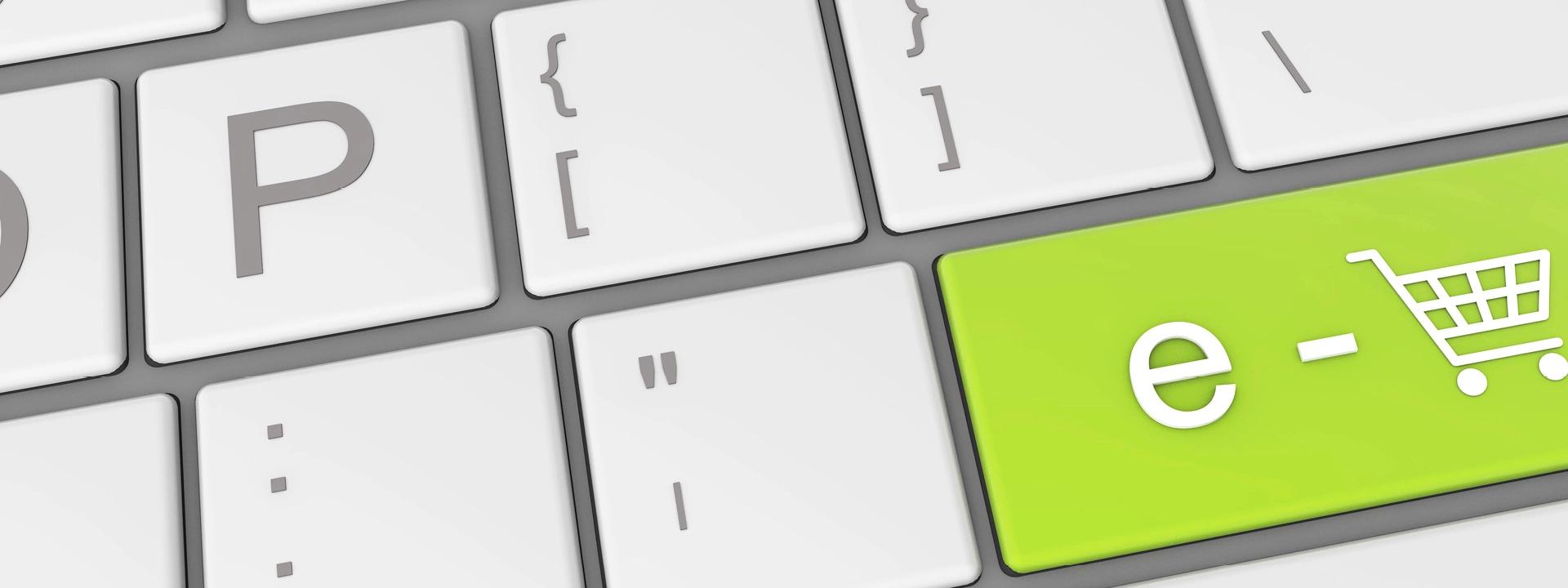 A close-up of a computer keyboard with a prominent green key featuring 'e-' and a shopping cart icon, symbolising PPC advertising specifically for e-commerce.