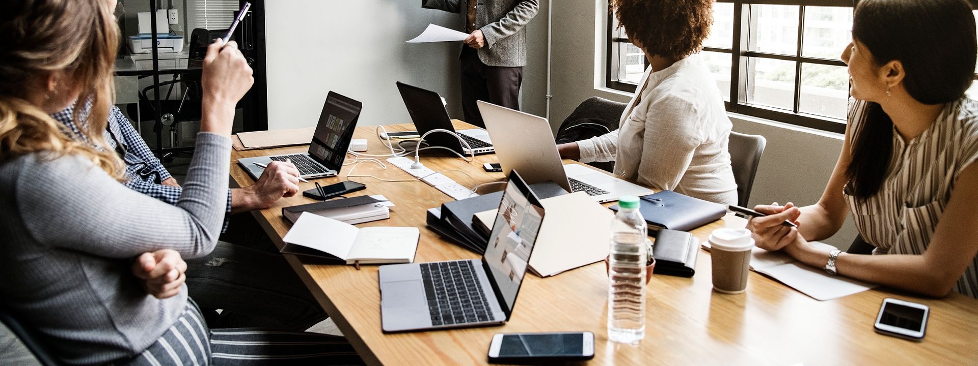 People gathered around a conference table with laptops and notebooks, engaged in an AdOps training session