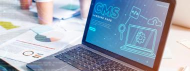 "A laptop displaying a 'CMS Landing Page' with various digital icons related to content management and development, set on a desk with documents and other office items, illustrating a focus on Sanity CMS or a similar content management system.