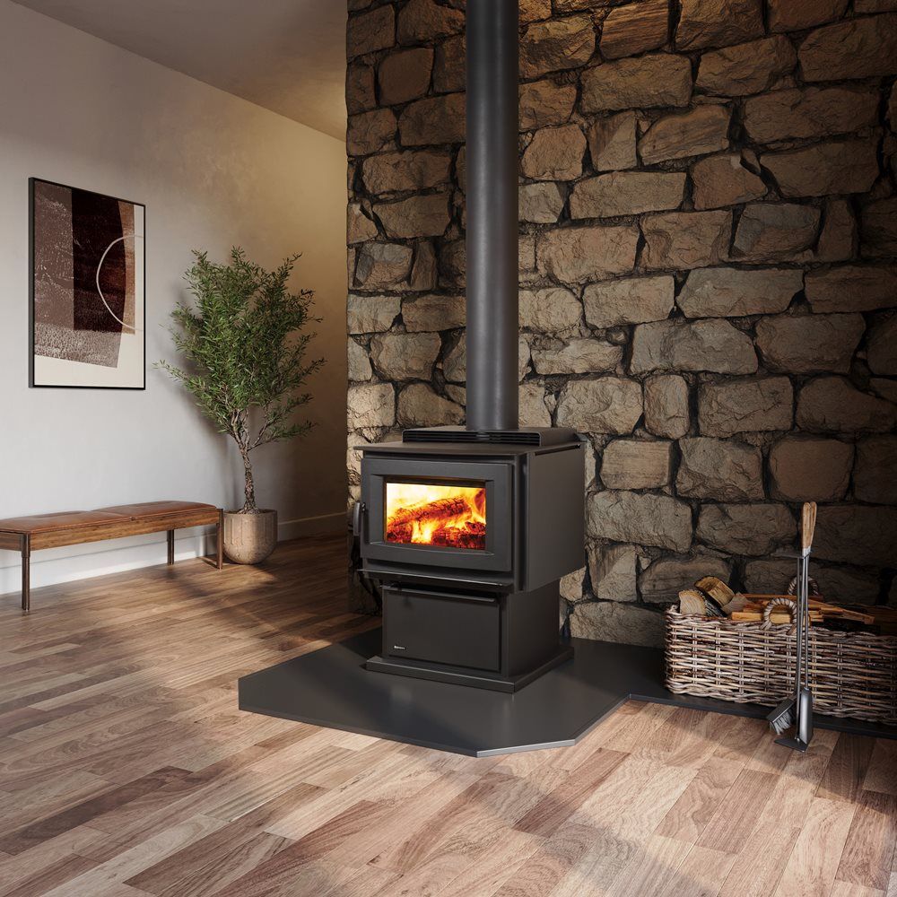 A modern wood-burning stove with a fire inside, set against a stone wall.