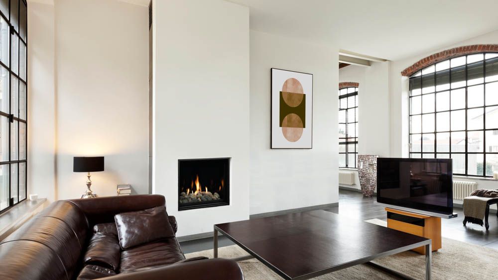 Modern living room with leather sofa, fireplace, and large windows.