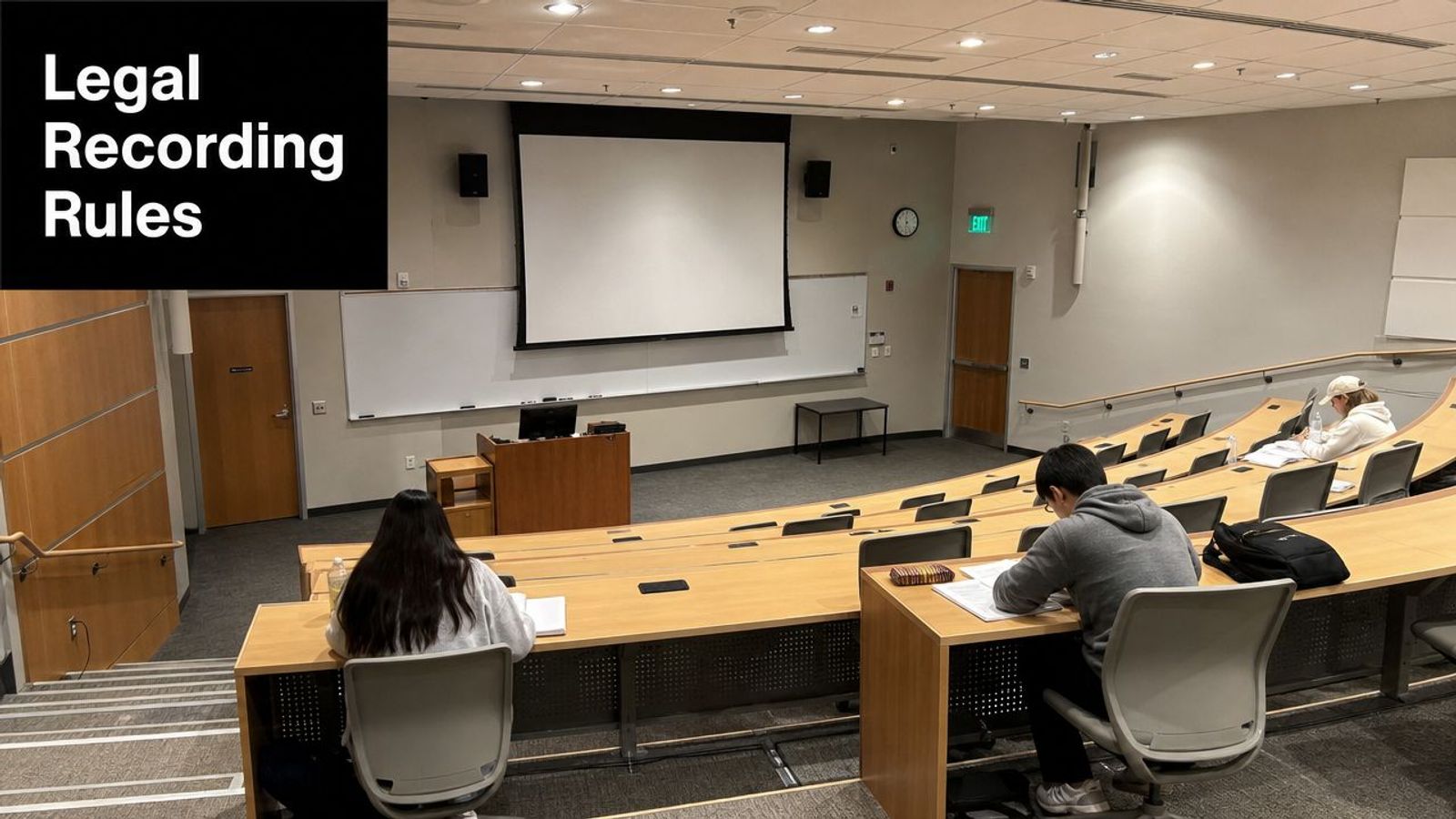 Students seated at wooden desks in a modern university lecture hall preparing for an academic presentation.