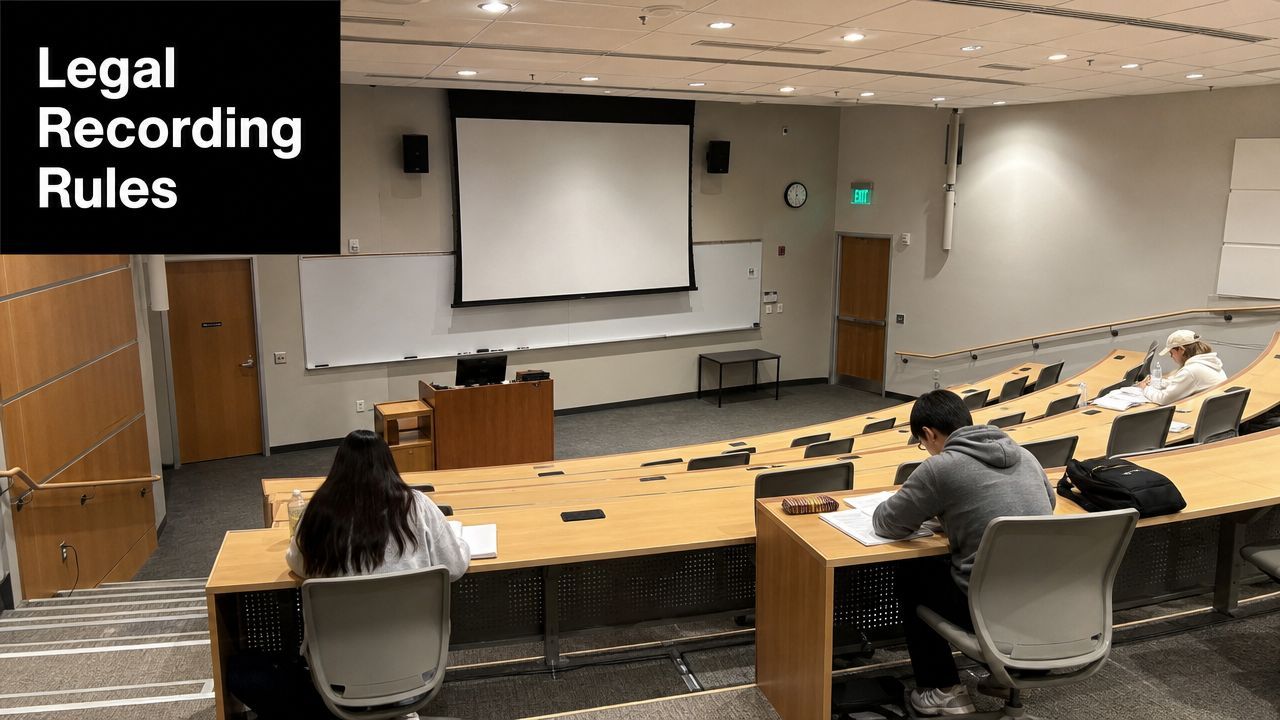 Students seated at wooden desks in a modern university lecture hall preparing for an academic presentation.
