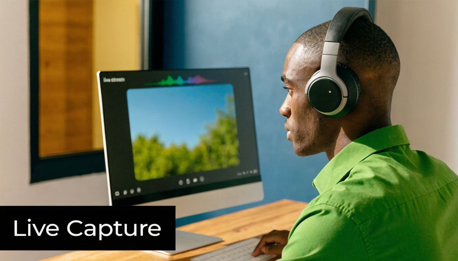 A person wearing headphones while looking at a computer monitor displaying a live stream interface.