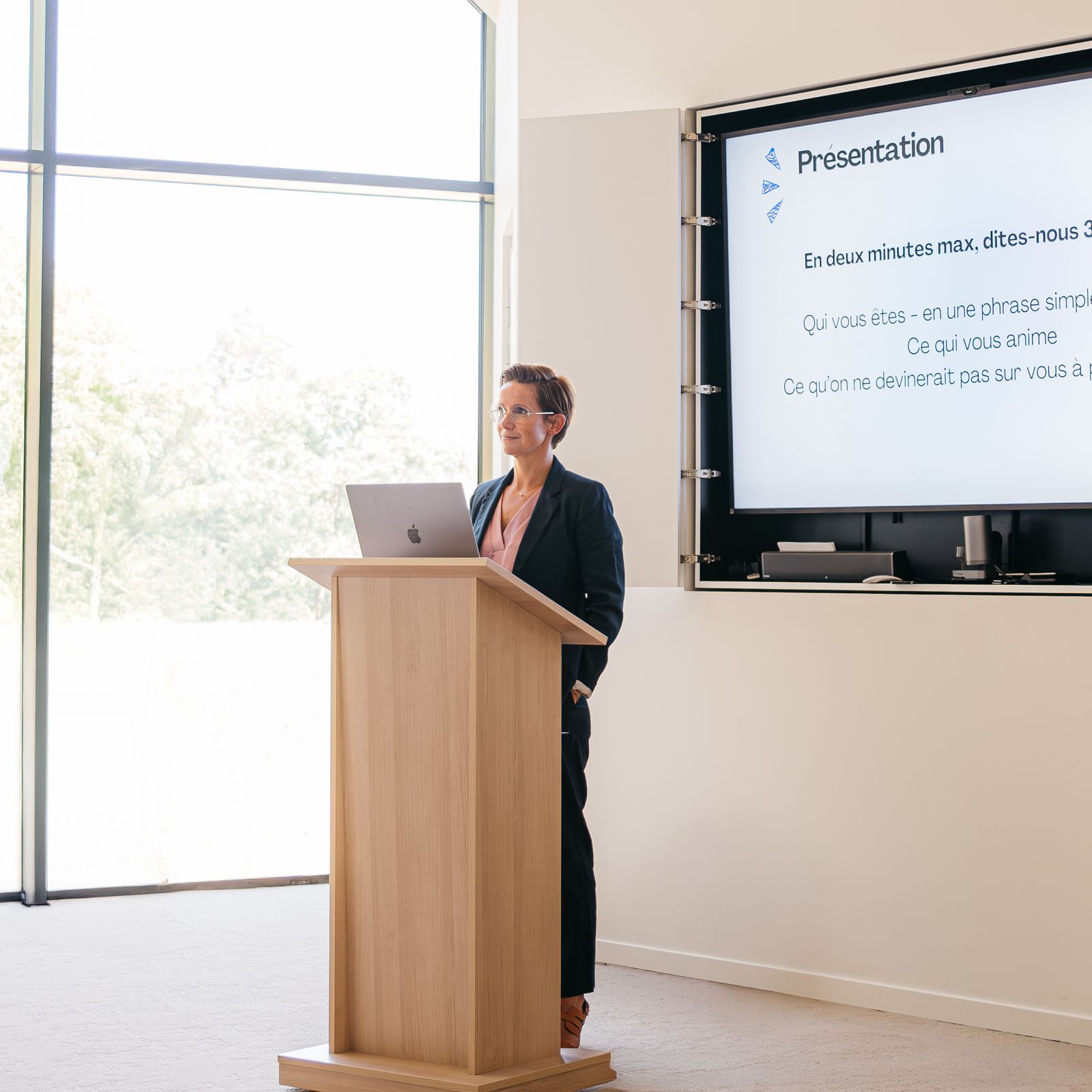Amélie Alleman presenting at a podium next to a digital screen.