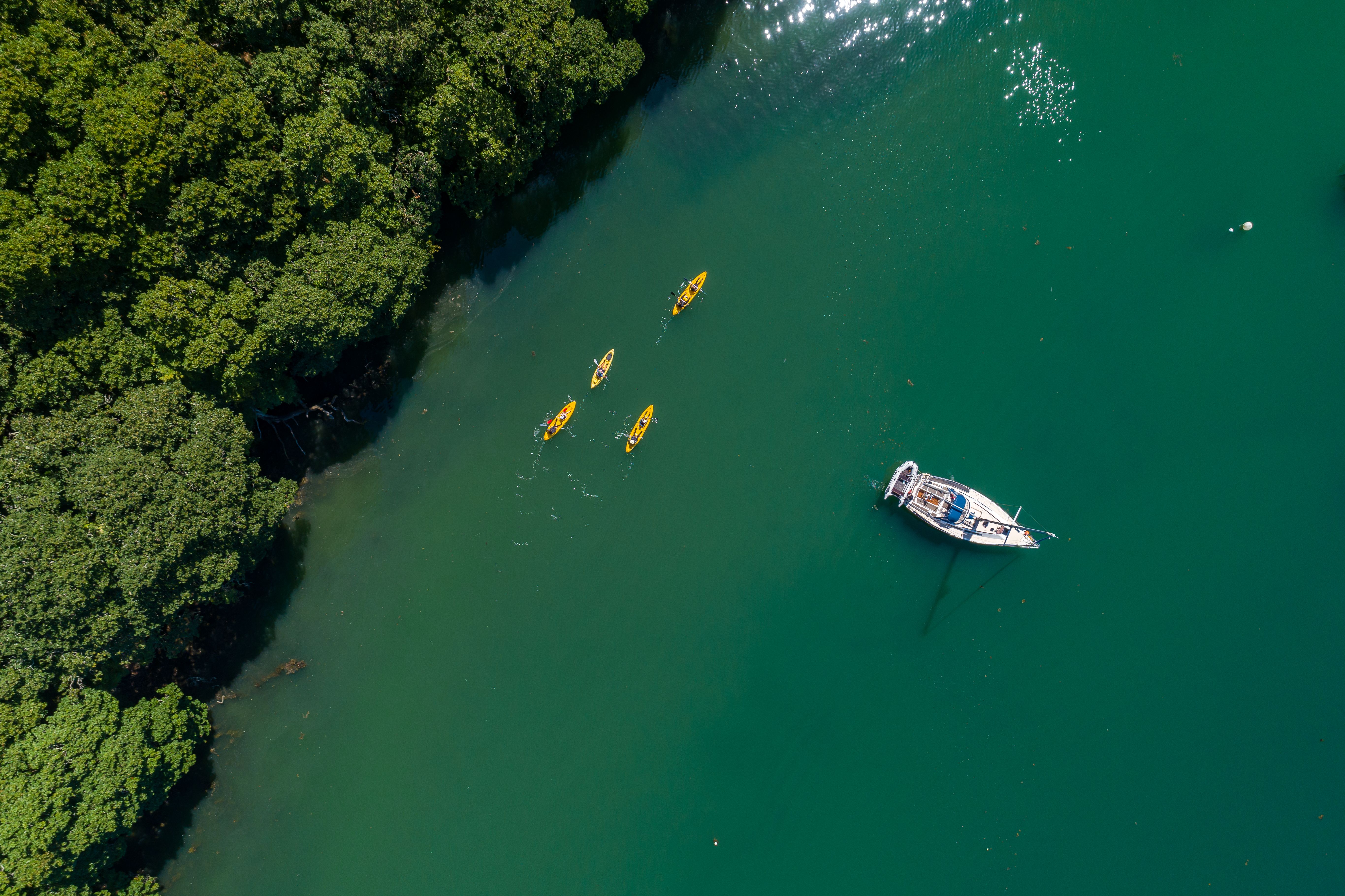 Aerial photo of four canoes and a yacht at anchor, Cornwall