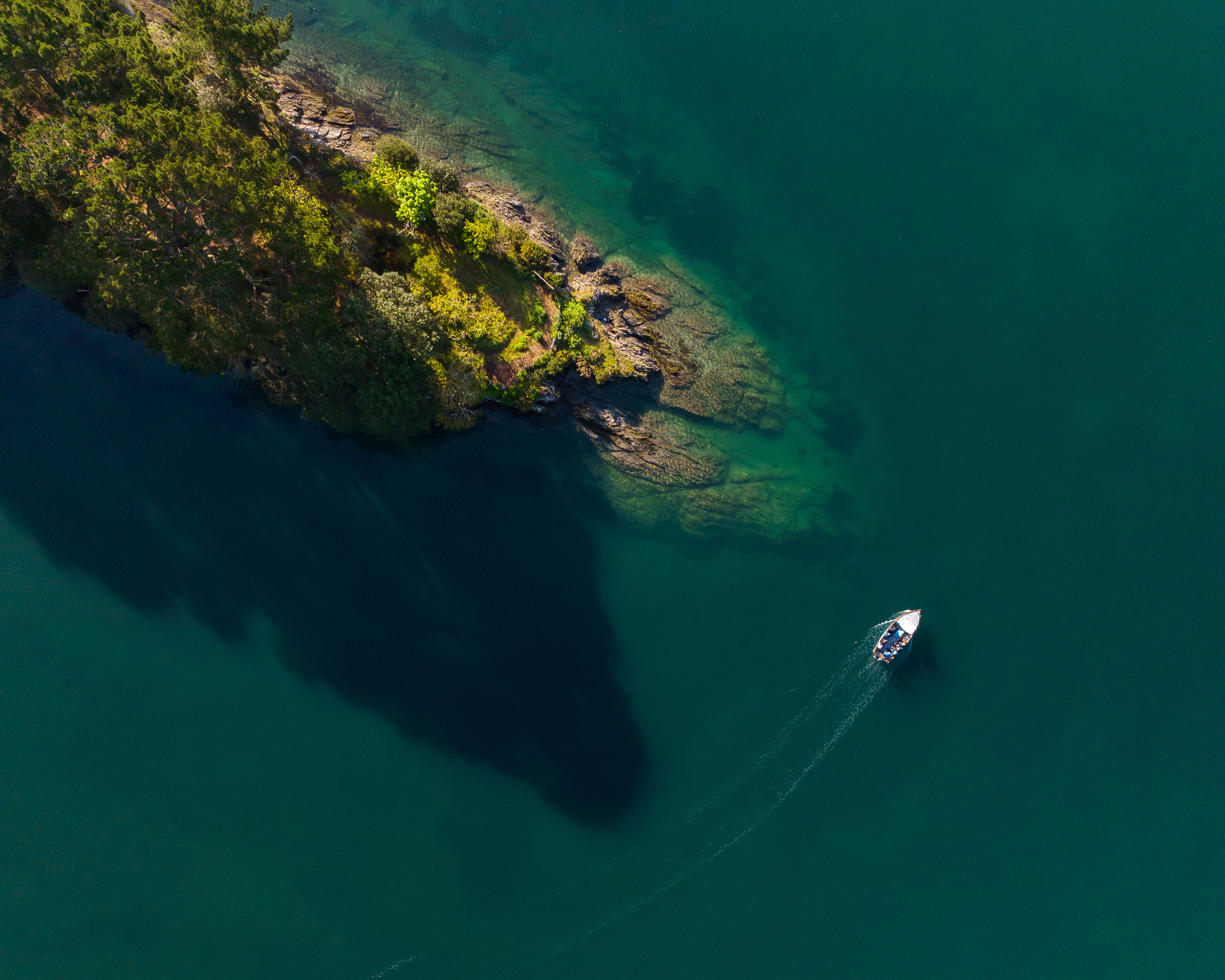 Aerial view of a boat sailing around a headland, Cornwall