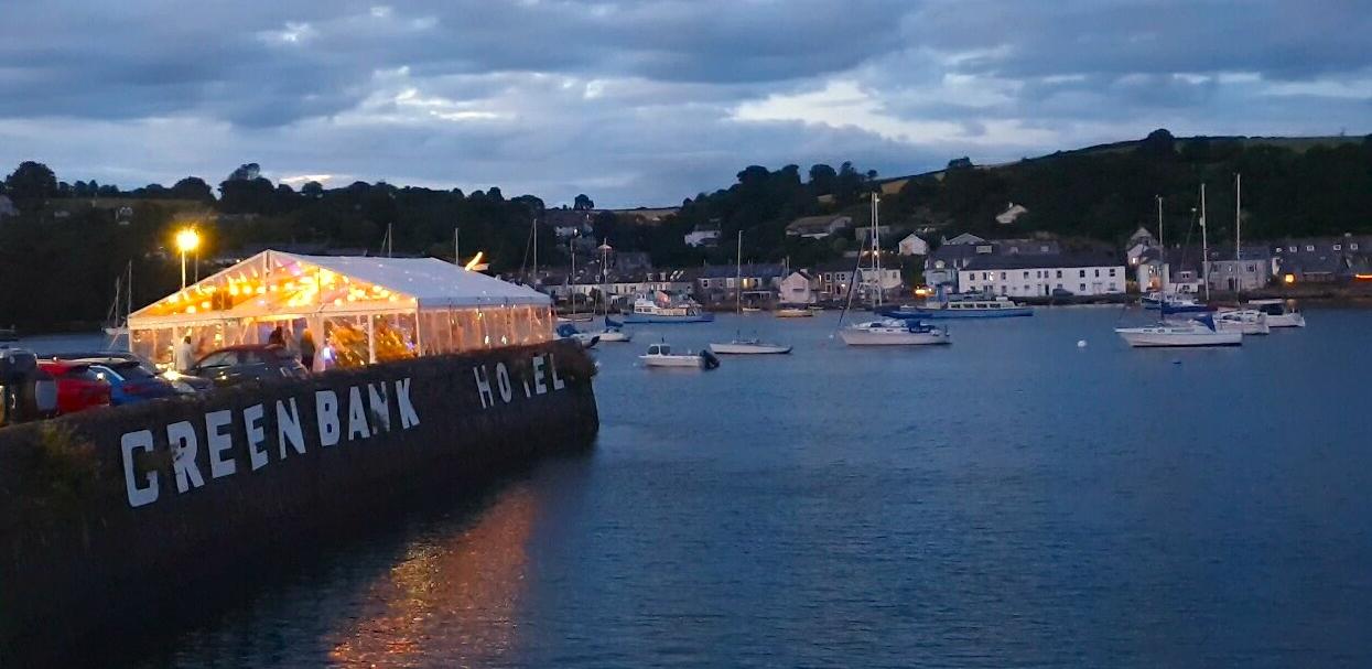 A photo at sunset of the quay at the Greenbank hotel with marquee and lights.