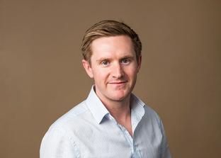 A photo of Jonty Brooks with a colorama backdrop