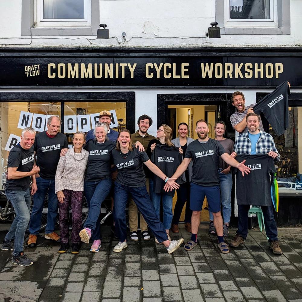 A group of cheerful people in front of the Draft & Flow Community Cycle Workshop