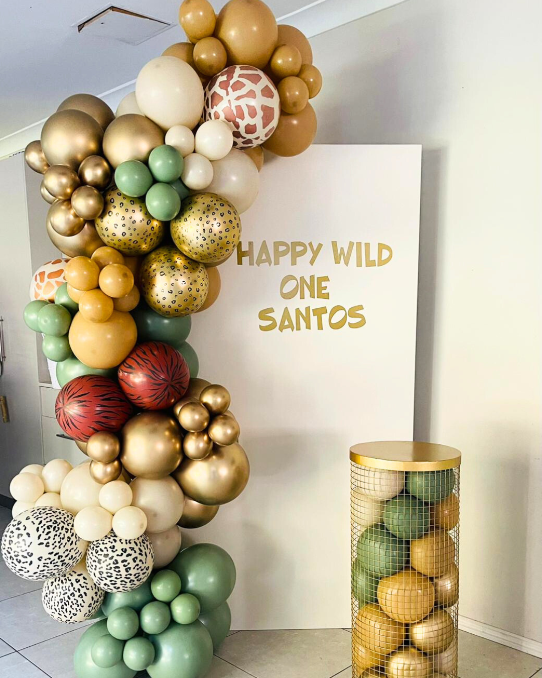 Wild jungle setup with animal prints balloon garland, custom backdrop and wired gold plinth