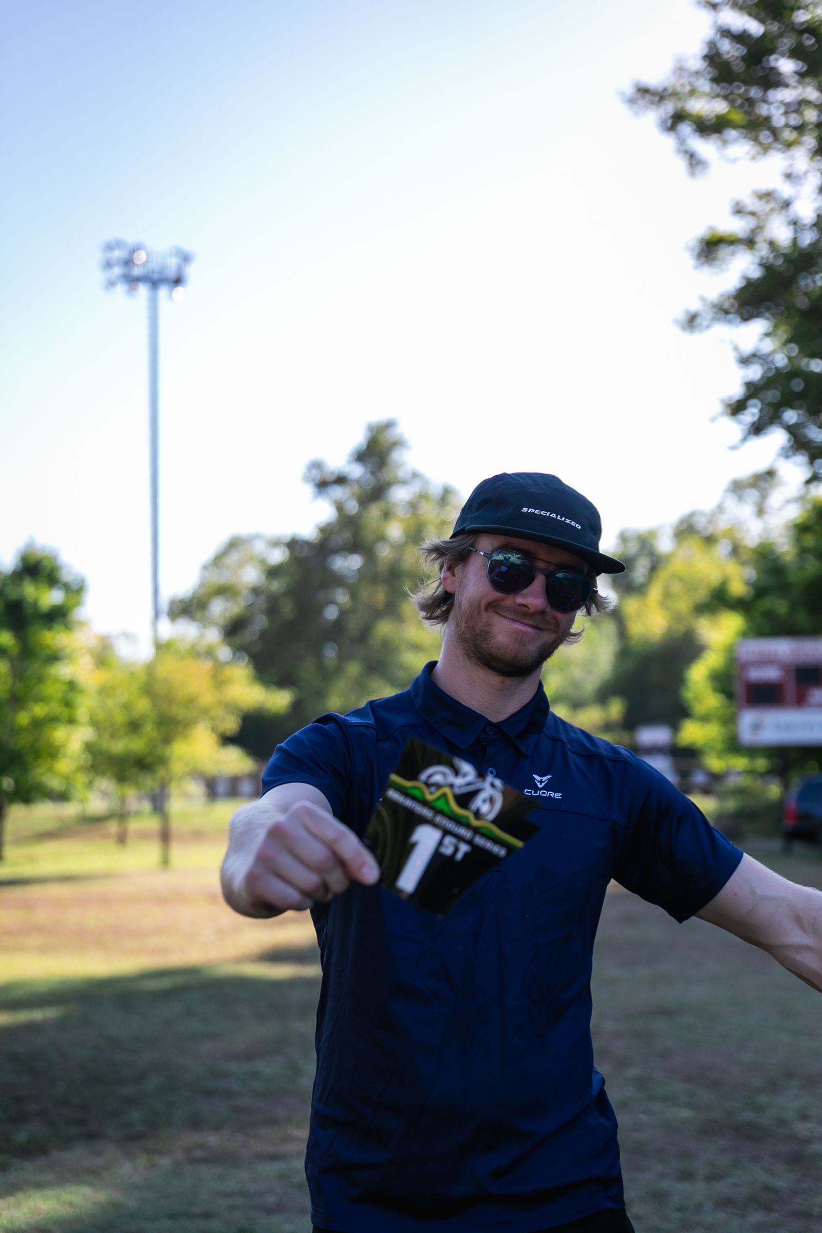 A smiling racer holds up a first-place plate at the race venue