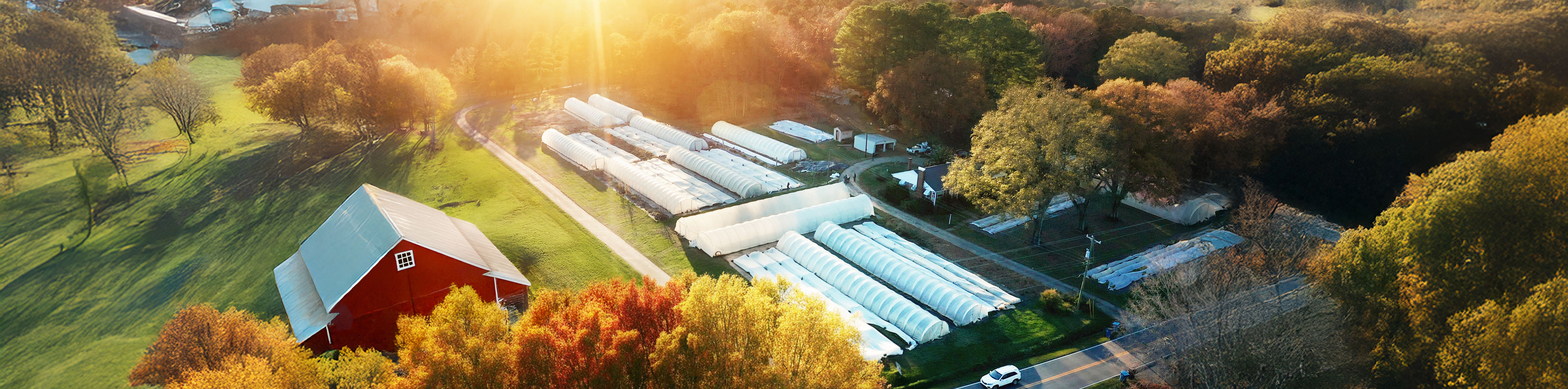 Image of farm with caterpillar tunnels and red barn.