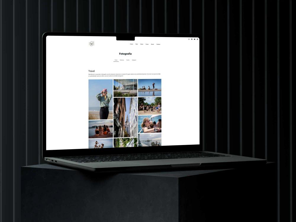 Laptop displaying a travel photo gallery website on a dark pedestal.