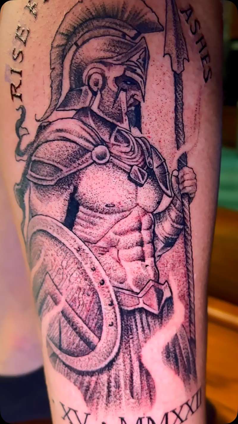 Black and grey illustrative Spartan warrior tattoo on upper arm