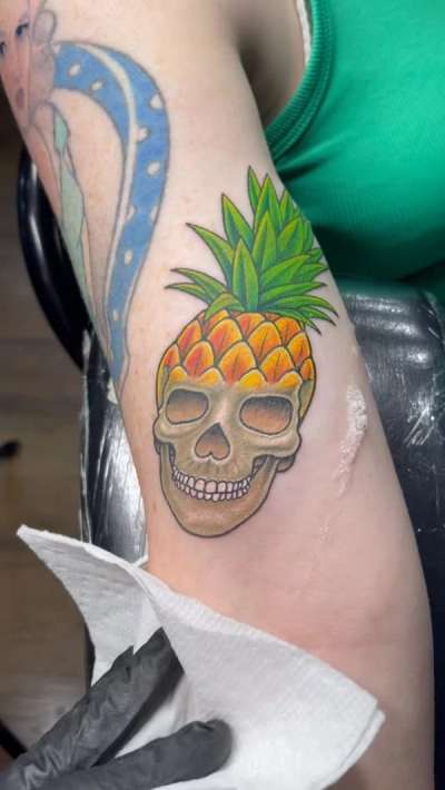 colorful pineapple skull tattoo on upper arm