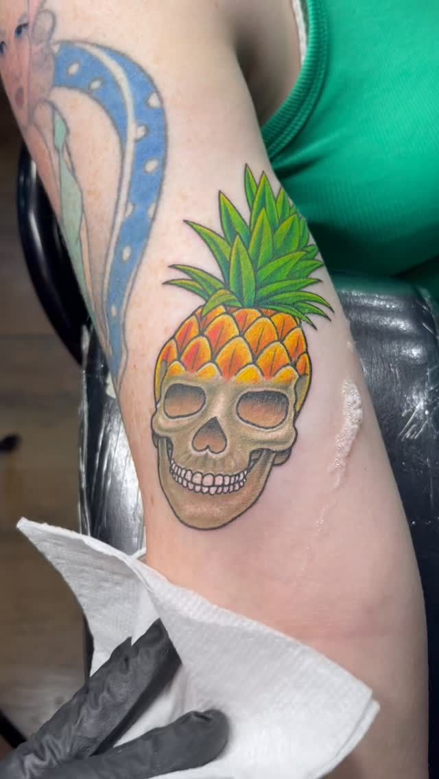 colorful pineapple skull tattoo on upper arm