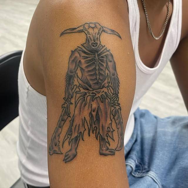 Black and grey illustrative mythical creature tattoo on upper arm