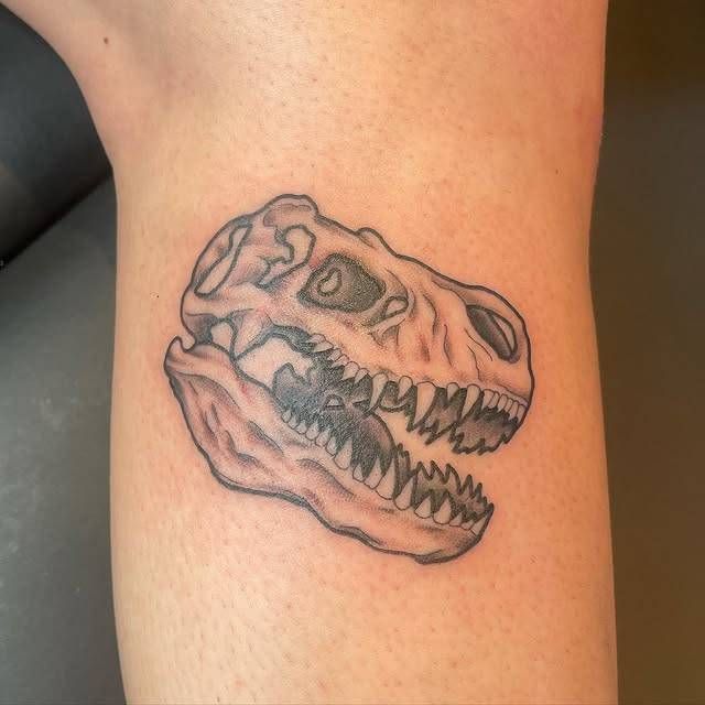Black and grey dinosaur skull tattoo on calf