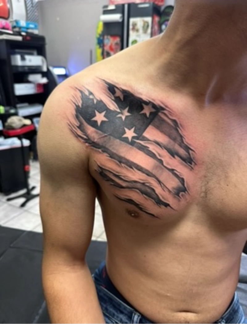 Black and grey realistic American flag tattoo on chest